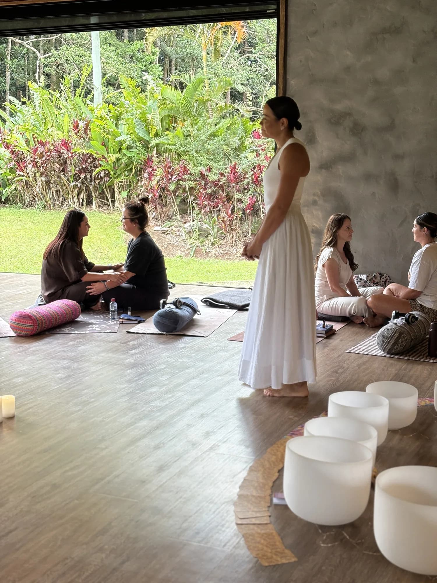 A circle of women gathered on mats in daylight