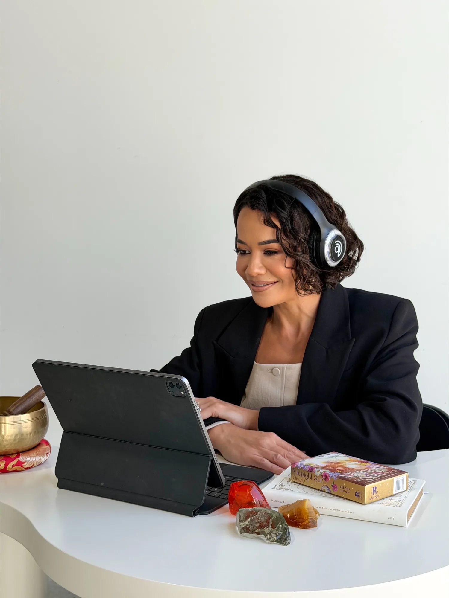 Delyse at her desk, headphones on, typing with a Tibetan bowl beside her